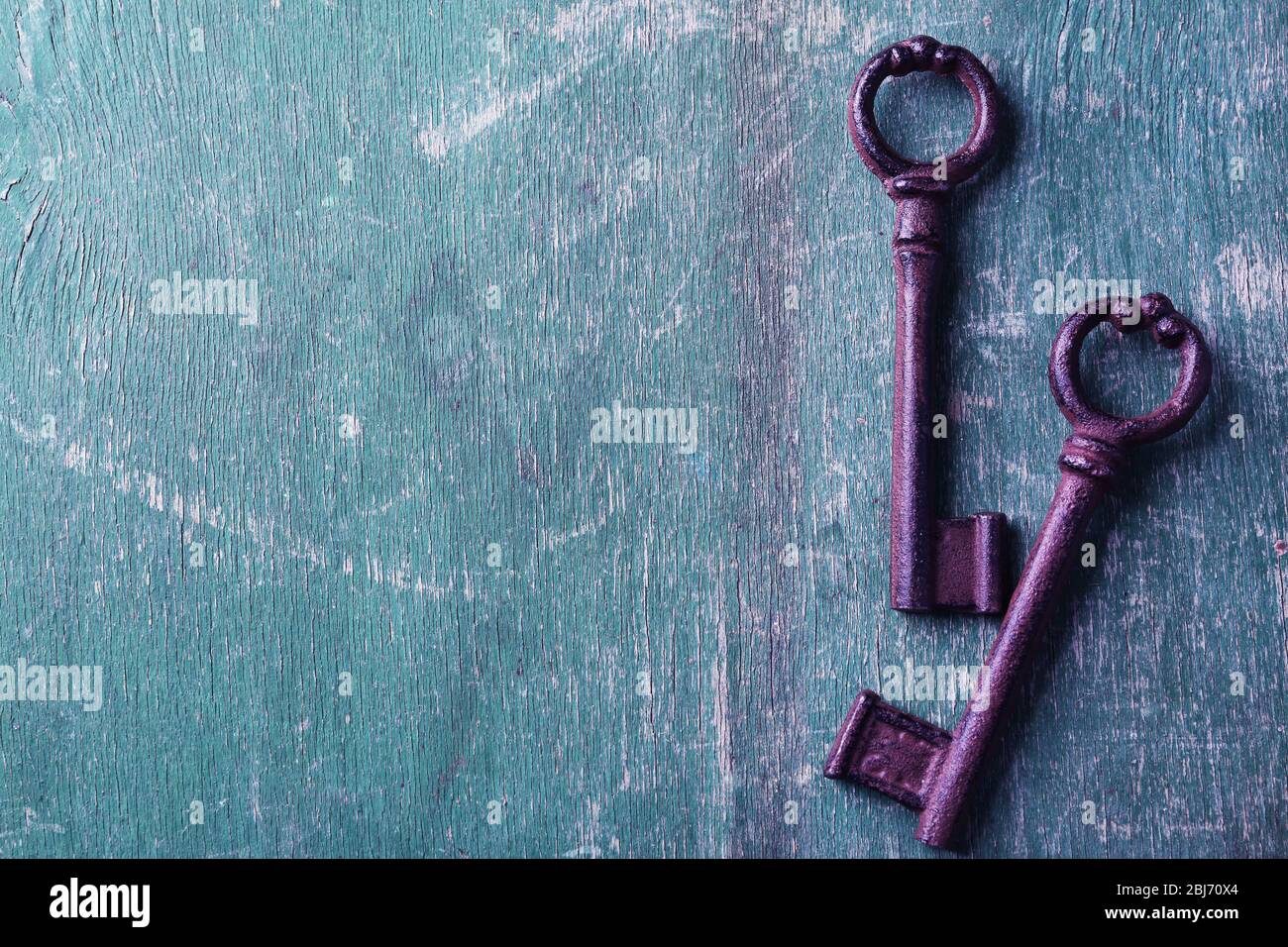 Alte Schlüssel auf grün verkratztem Holzhintergrund, kopieren Raum Stockfoto