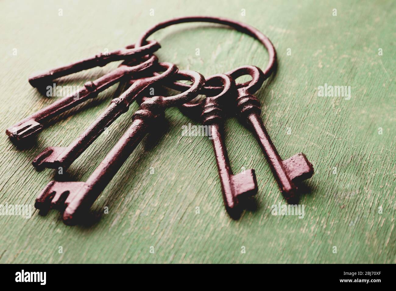 Ein Haufen alter Schlüssel auf grün verkratztem Holzhintergrund, Nahaufnahme Stockfoto