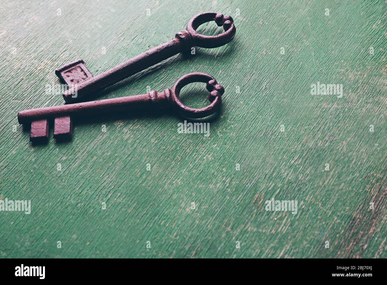Alte Schlüssel auf grün verkratztem Holzhintergrund, kopieren Raum Stockfoto