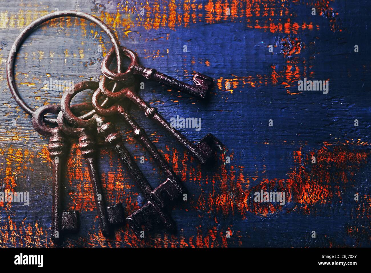 Ein Haufen alter Schlüssel auf blauem, zerkratztem Holzhintergrund, Nahaufnahme Stockfoto