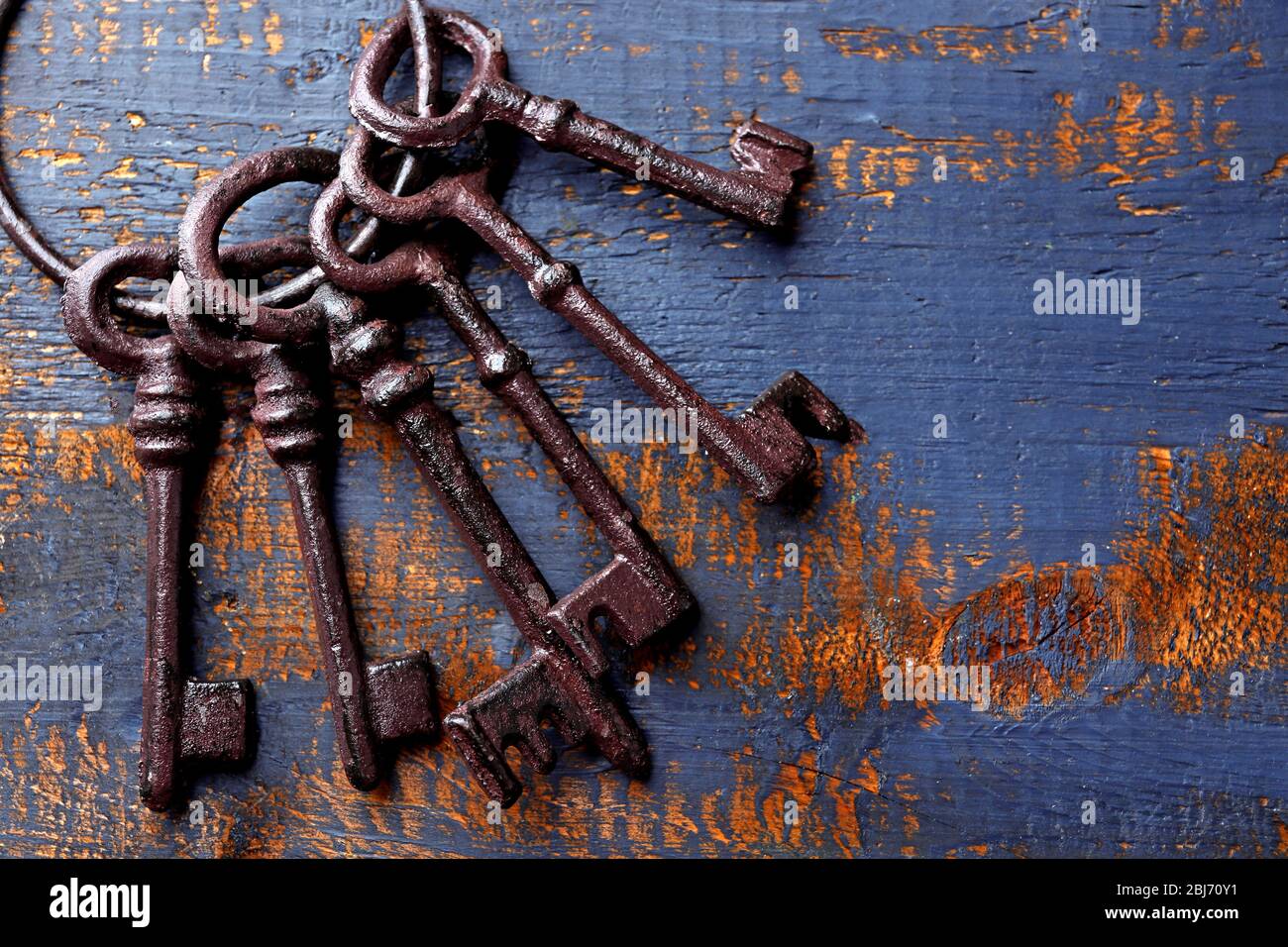 Ein Haufen alter Schlüssel auf blauem, zerkratztem Holzhintergrund, Nahaufnahme Stockfoto