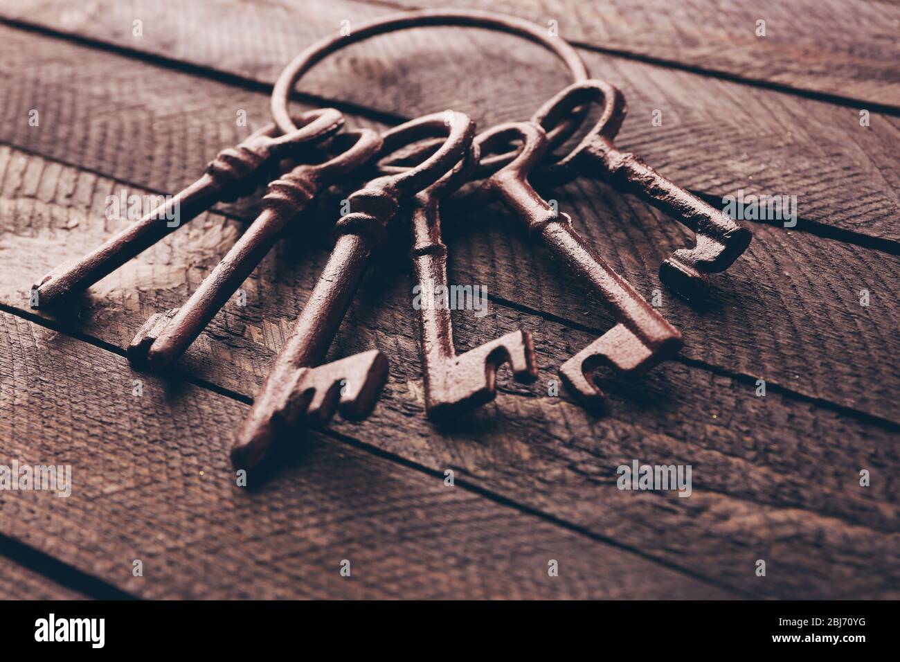 Haufen alter Schlüssel auf dunklem Holzhintergrund, Nahaufnahme Stockfoto