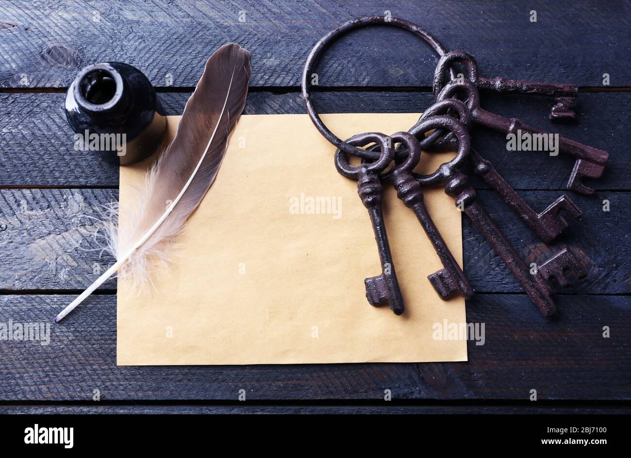Ein Haufen alter Schlüssel mit Papier, Tinte und Stift auf dunklem Holzhintergrund, Nahaufnahme Stockfoto