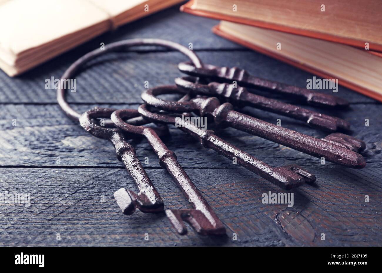 Haufen alter Schlüssel mit Notizbüchern auf dunklem Holzhintergrund, Nahaufnahme Stockfoto