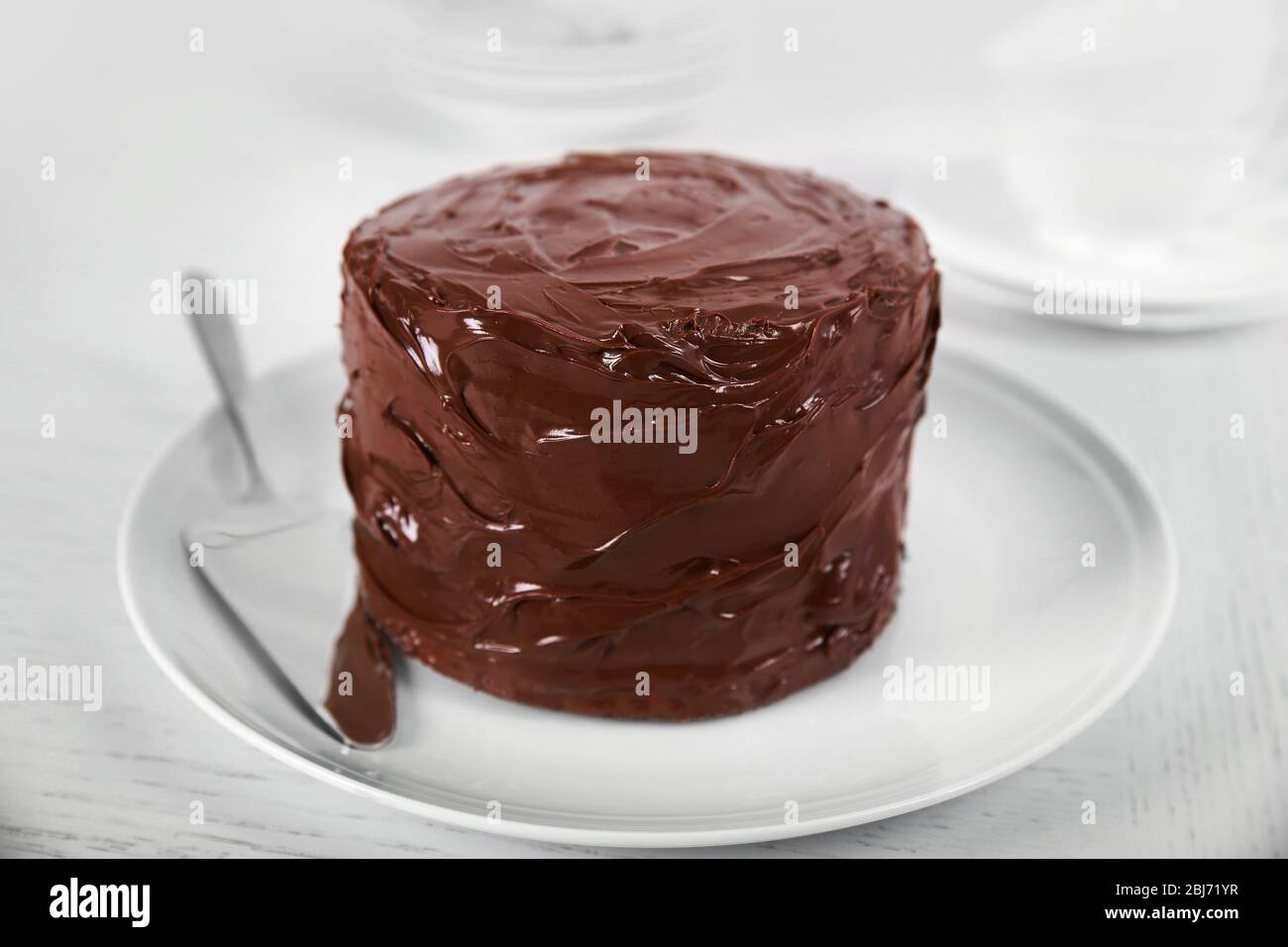 Schokoladenkuchen auf einem Teller mit Klinge auf hellem Hintergrund Stockfoto