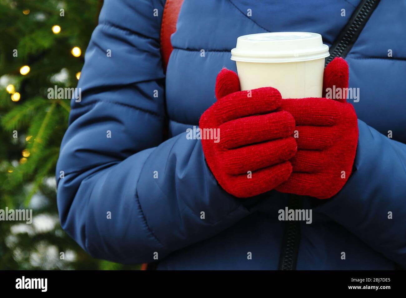 Weibliche Hände in Fäustlinge mit Tasse Kaffee Nahaufnahme Stockfoto