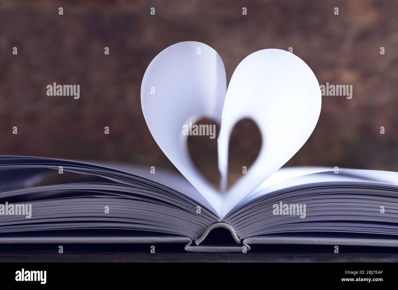 Herz aus Buchseiten auf Holzhintergrund verschwommen Stockfoto