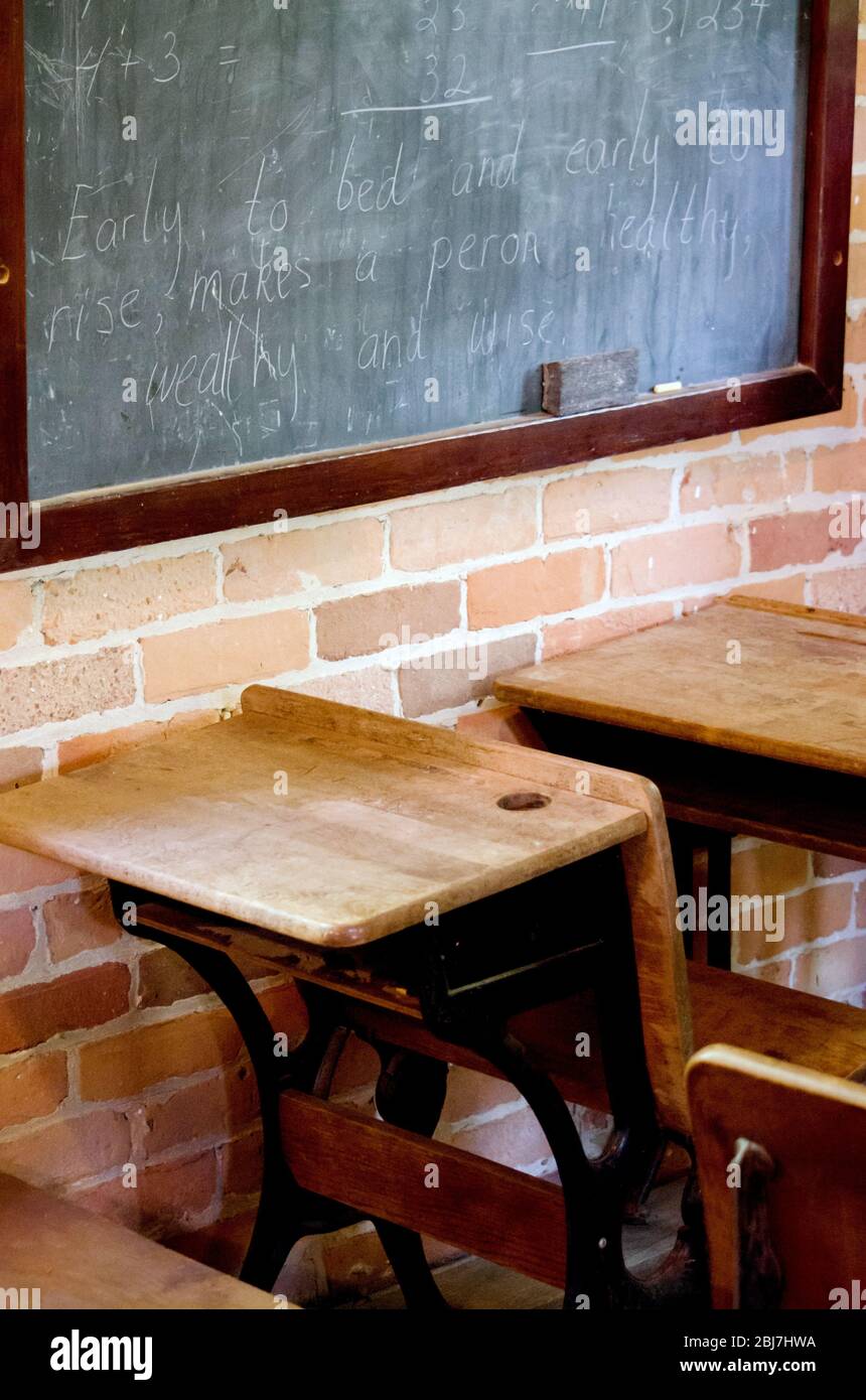 Altmodische Schulschreibtische sitzen leer von einer Kreidetafel, in diesem Vintage-Schulklasse-Zimmer Stockfoto