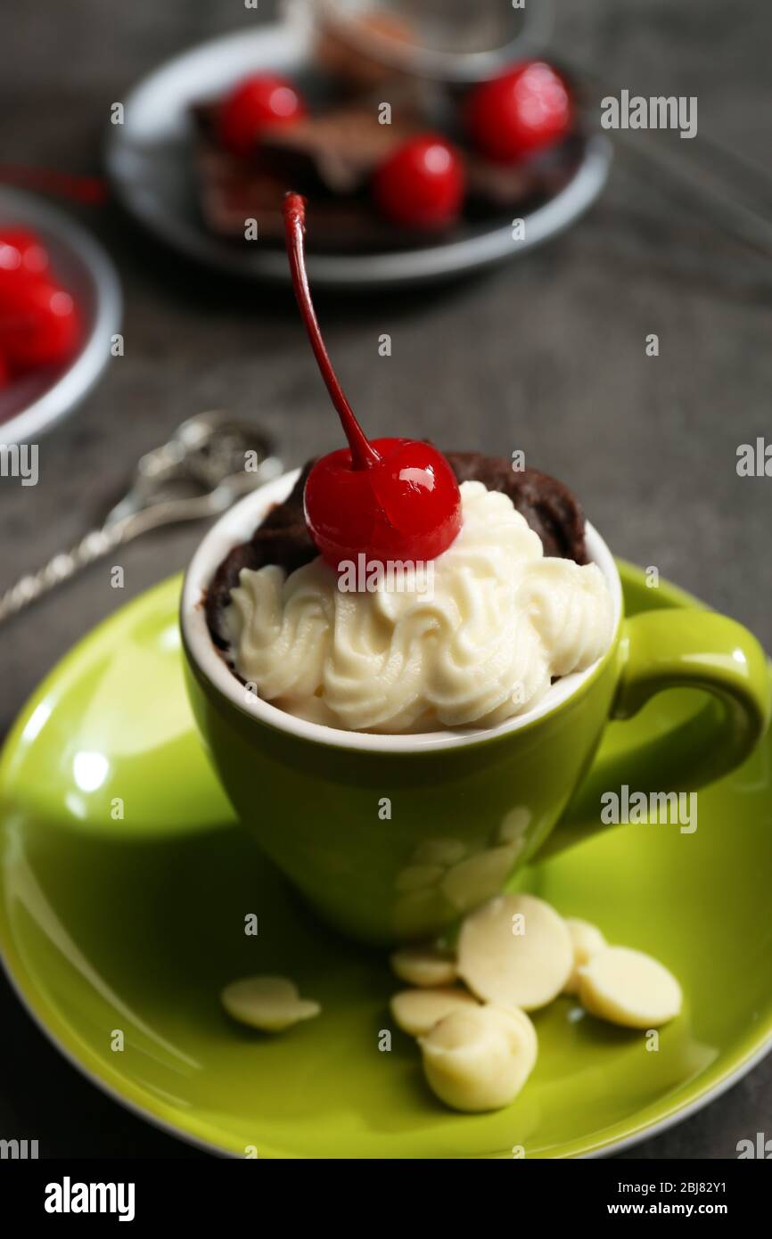 Schokoladenkuchen in einem grünen Becher serviert mit zwei Tellern Kirschen und Schokolade, aus nächster Nähe Stockfoto