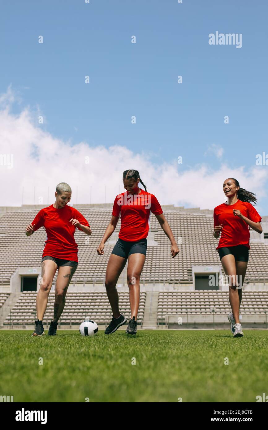 Drei Frauen spielen Fußball während des Mannschaftspraktik im Feld. Frauen Fußballspieler auf dem Sportplatz spielen. Stockfoto