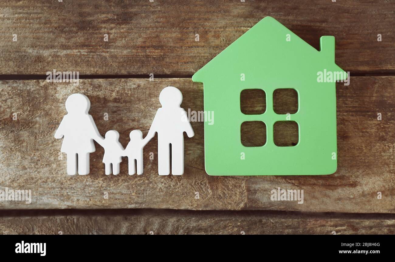 Familienfigur mit einem Haus auf Holzhintergrund Stockfoto