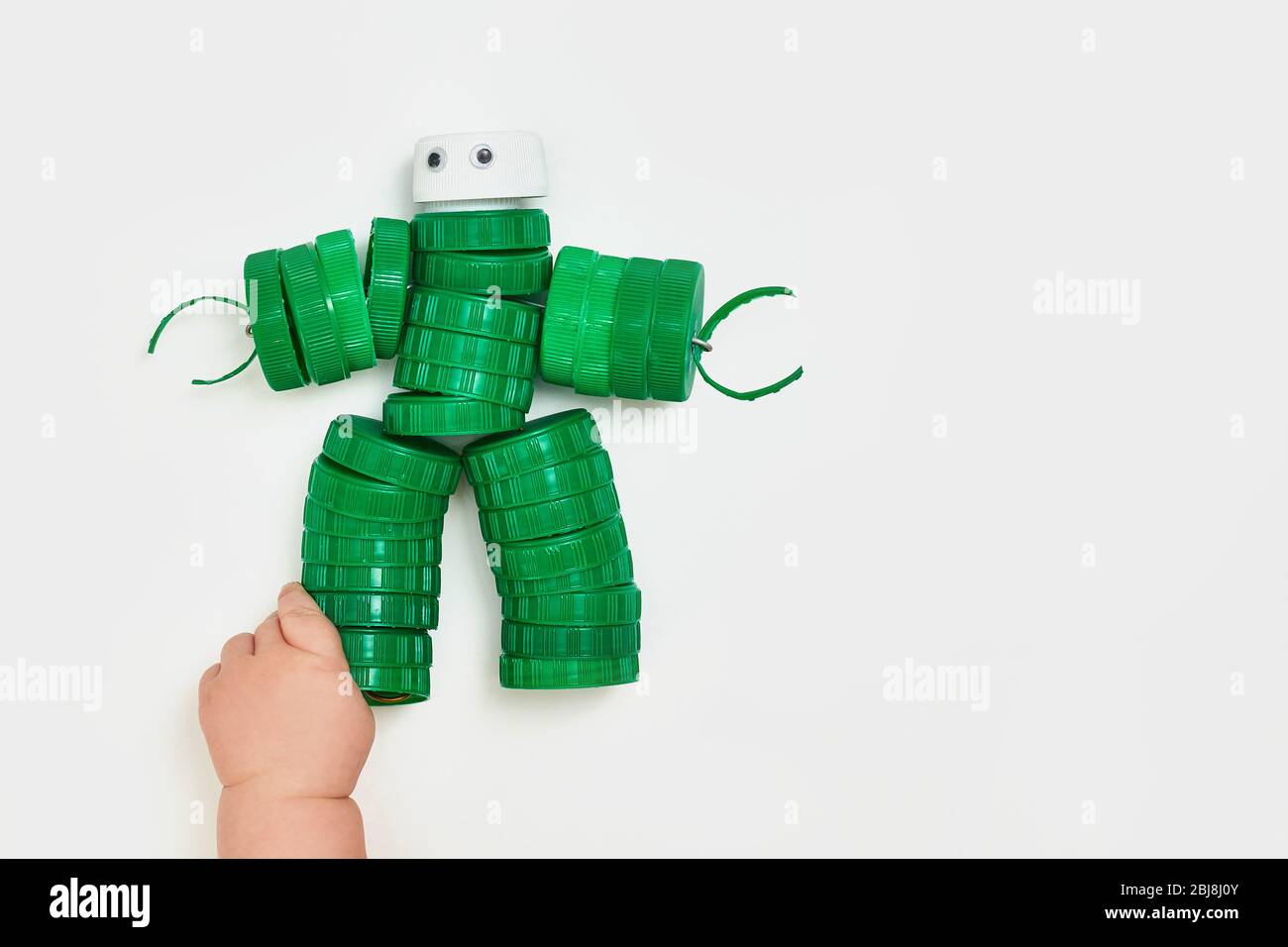 Null Verschwendung, das zweite Leben der Dinge. Spielzeugroboter aus Kunststoffkappen auf weißem Hintergrund. Gesichtslos. Recycling Kunst. Copyspace. Stockfoto