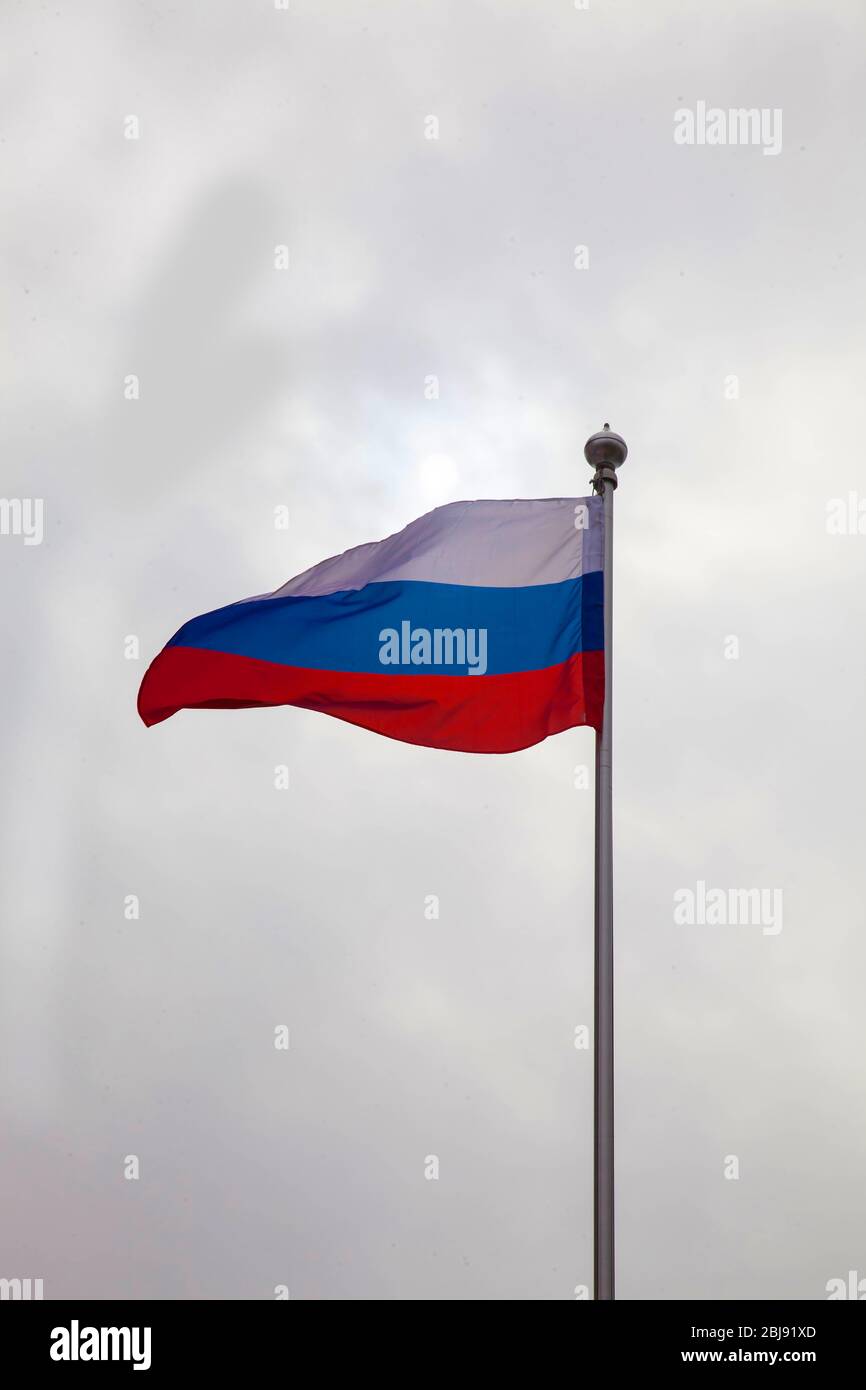 Die russische Flagge fliegt auf einem Fahnenmast gegen den Himmel Stockfoto