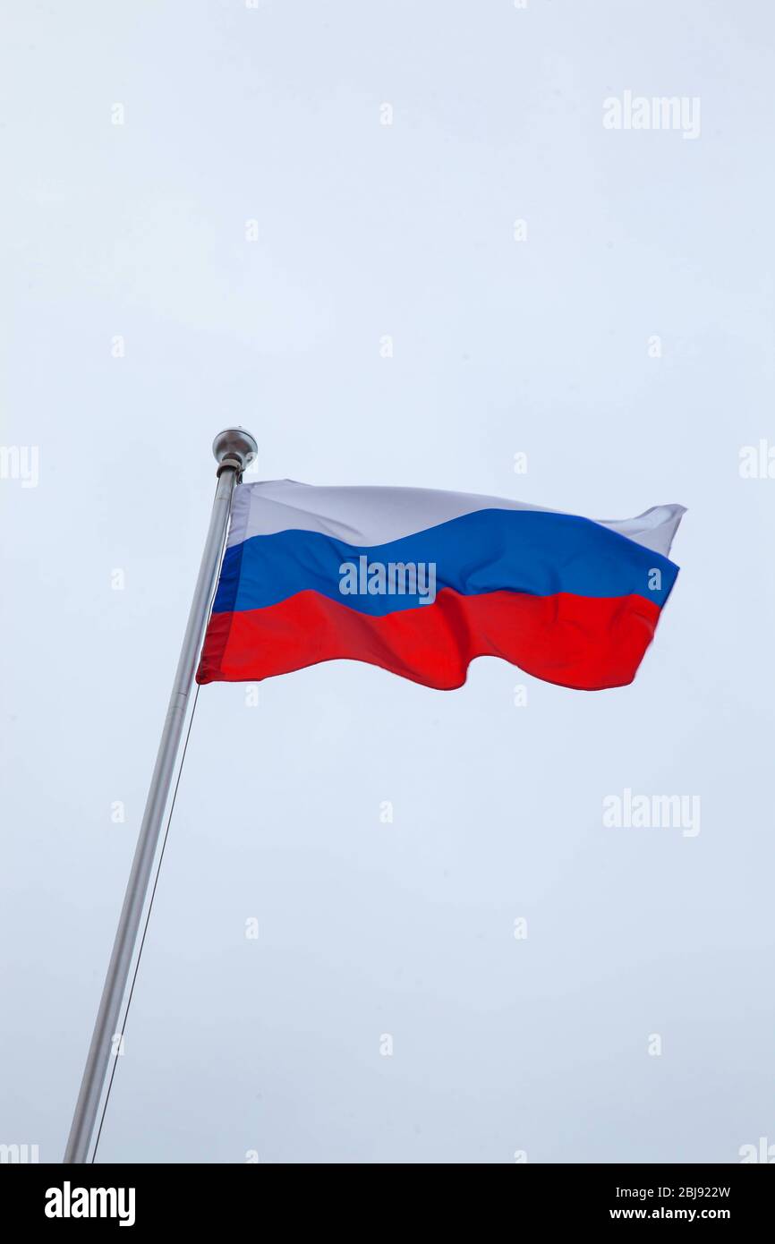 Die russische Flagge fliegt auf einem Fahnenmast gegen den Himmel Stockfoto