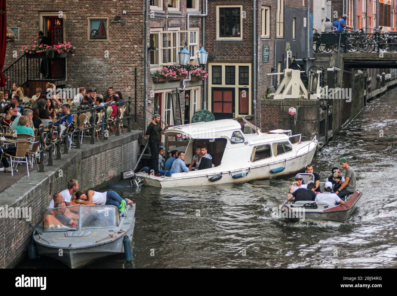 Zufällige Menschen auf und über den Kanal in Amsterdam, Niederlande Stockfoto