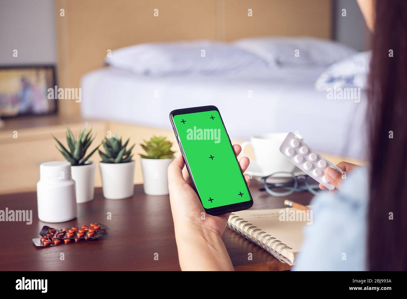 Kranke Frau verwenden Videokonferenz, Online-Beratung mit Arzt auf mobile Anwendung, Smartphone mit leeren grünen Bildschirm für Kopierraum. Telehe Stockfoto
