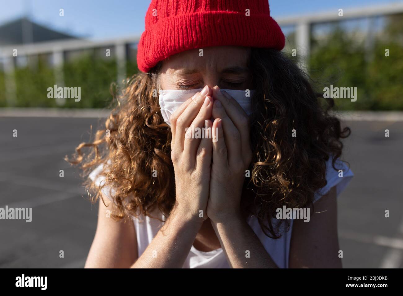 Kaukasische Frau mit einer Schutzmaske und hustet auf den Straßen Stockfoto