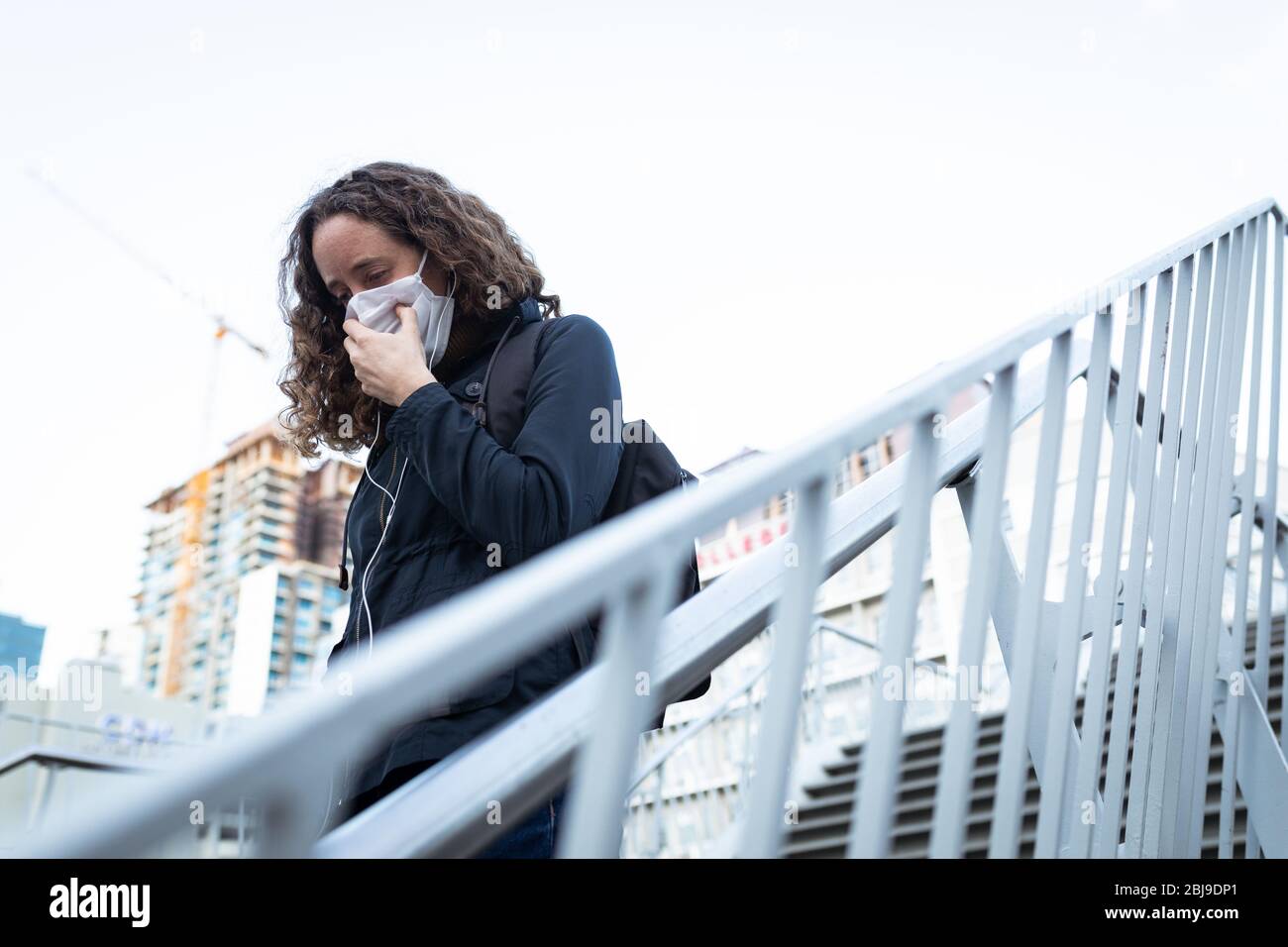 Kaukasische Frau mit einer Schutzmaske und zu Fuß die Treppe hinunter Stockfoto