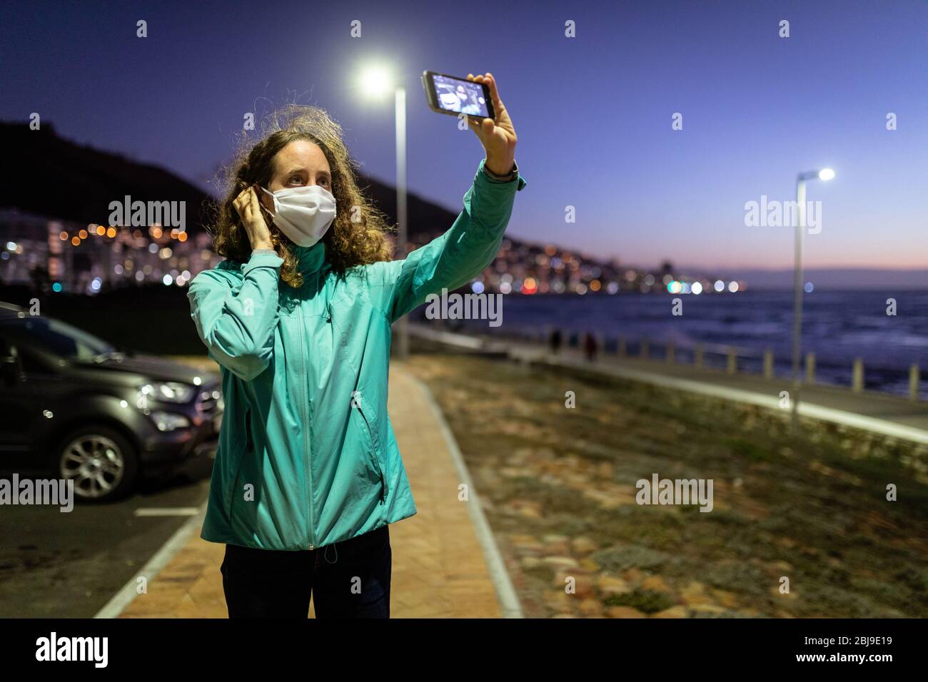 Kaukasische Frau mit einer Schutzmaske gegen Coronavirus, ein Foto auf der Straße Stockfoto