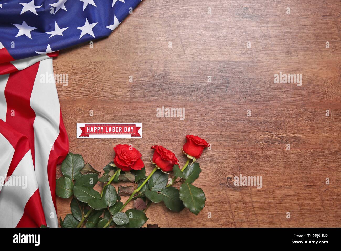 Rosen und amerikanische Flagge auf einem hölzernen Hintergrund. Konzept des Arbeitstages Stockfoto