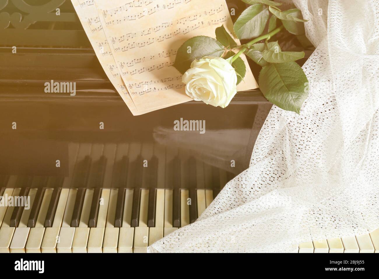 Weiße Rose mit Noten auf Klaviertasten Stockfoto