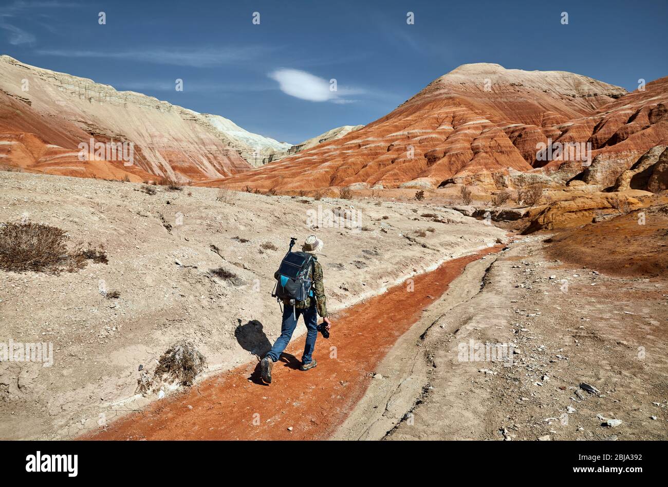 Tourist mit Rucksack und Kamera gehen an die staubige Canyons auf surreale roten Bergen gegen den blauen Himmel in der Wüste Stockfoto