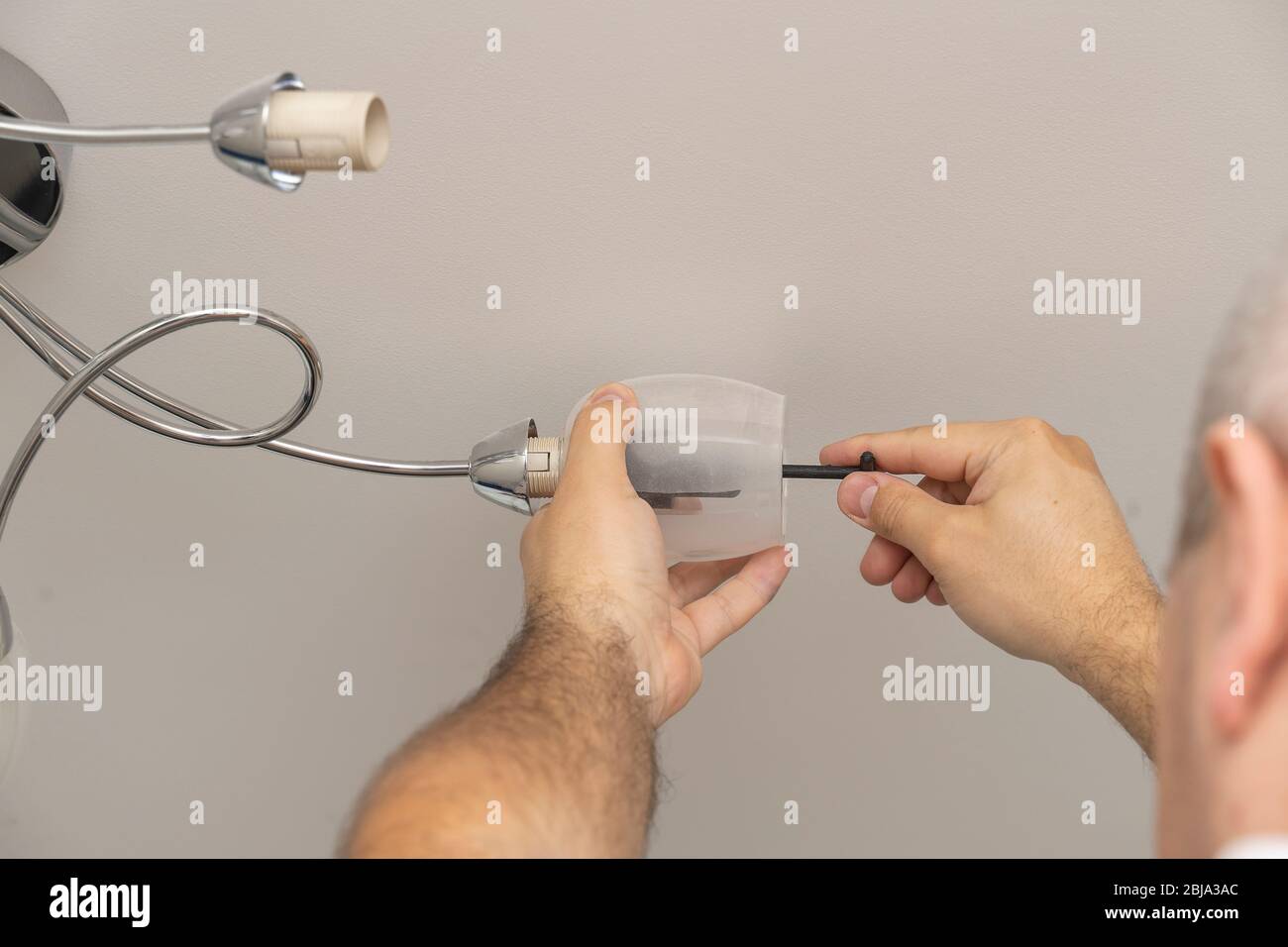 Mann wechselt eine Glühbirne in einem Beleuchtungsgerät, Lampe Twist. Stockfoto
