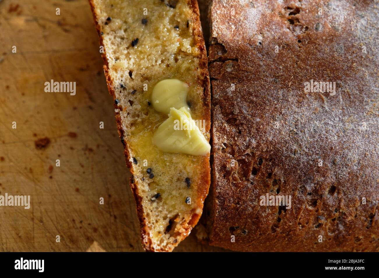 Eine Scheibe warmes Brot wurde zu essen gebuttert Stockfoto