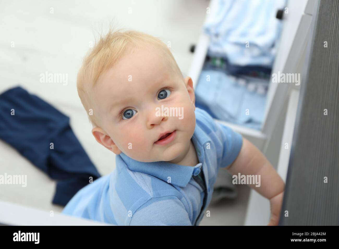 Baby wirft Kleidung aus Holzkiste Stockfoto