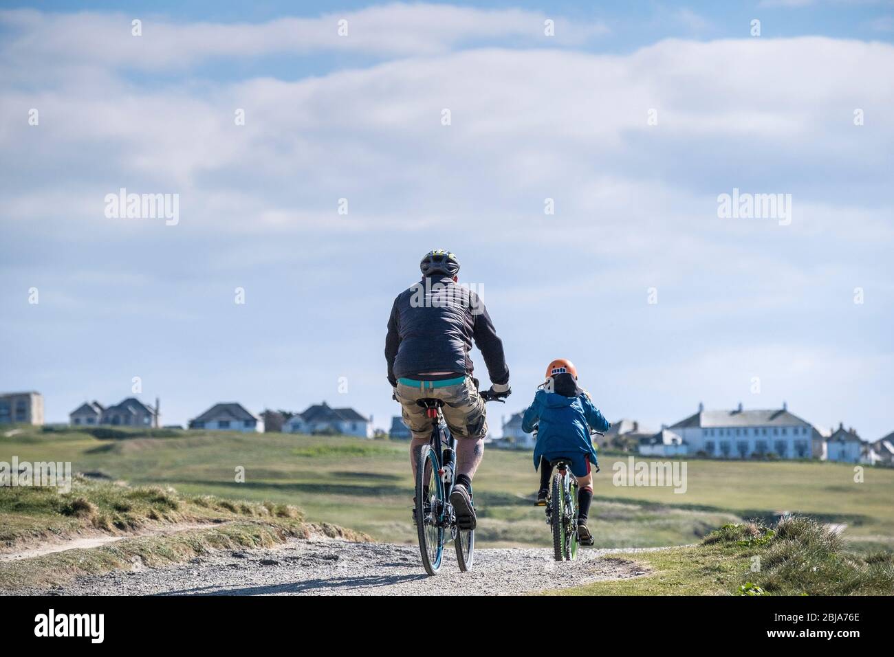 Ein Vater und ein Kind radeln gemeinsam auf einem Weg in Newquay in Cornwall. Stockfoto