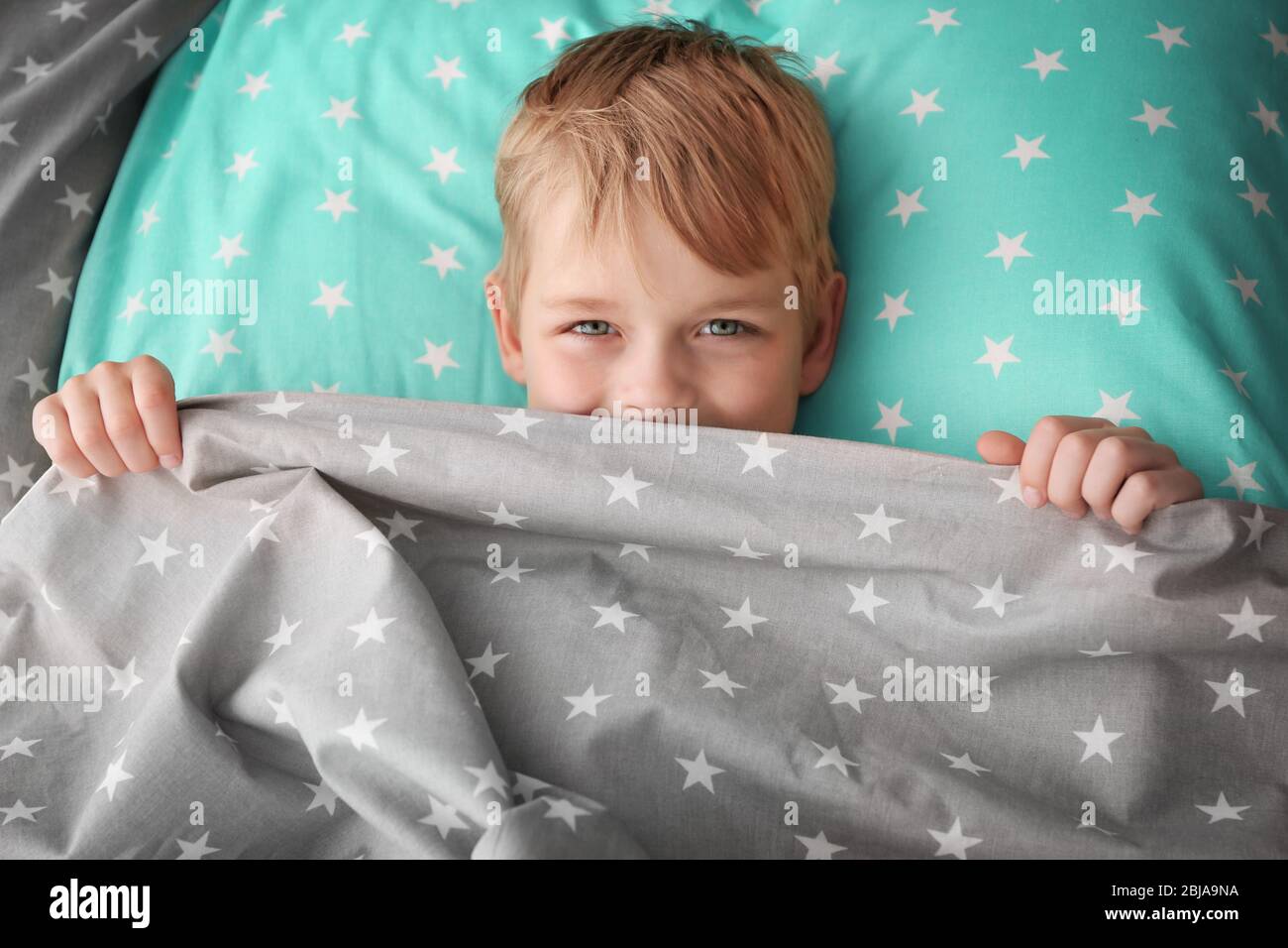 Liebenswert kleinen Jungen versteckt unter Bettlaken Stockfoto