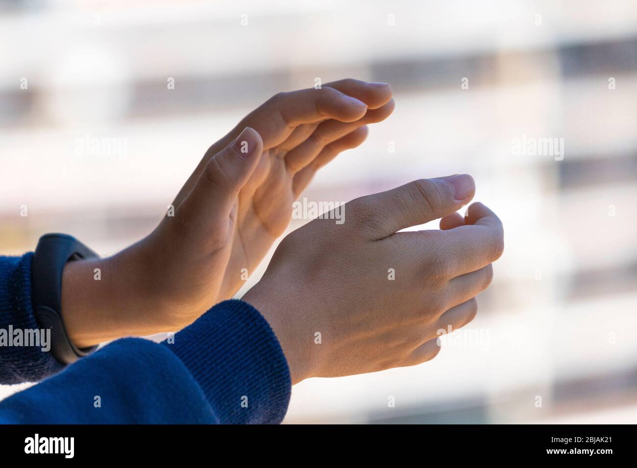 Beifall. Kind klatscht Hände, applaudieren vom Balkon, um Ärzte, Krankenschwestern, Krankenhausmitarbeiter während der Coronavirus-Pandemie Quarantäne zu unterstützen Stockfoto