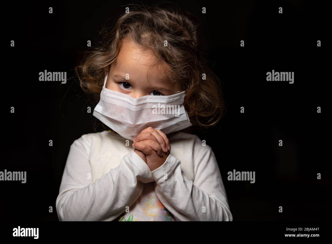 Mädchen trägt Maske zum Schutz gegen Covid-19 Coronavirus Pandemie. Sie betet Gott um Heilung und Hilfe. Kopierbereich. Stockfoto