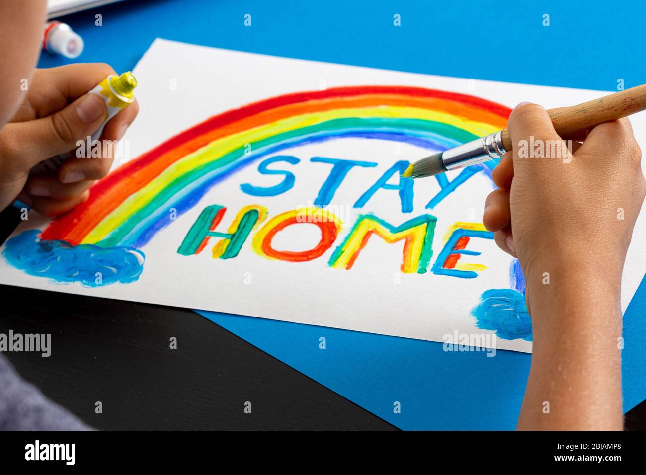 Junge Malerei während der Quarantäne zu Hause. Regenbogen mit Worten Bleib zu Hause. Social Media Kampagne zur Prävention von Coronavirus Stockfoto