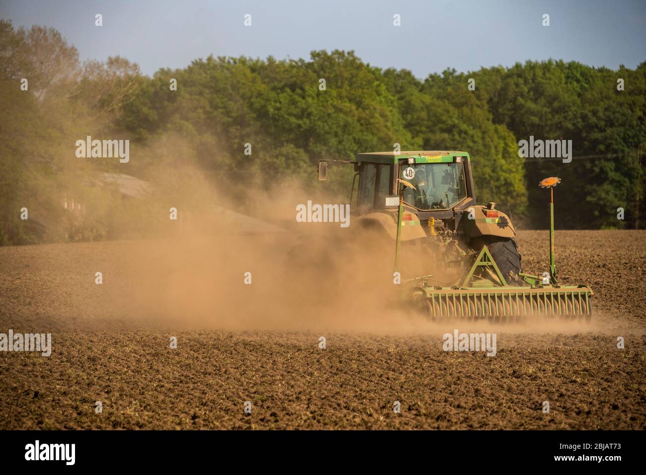 Bauer, der die Felder im Frühjahr, trocken April 2020, Traktor zieht dicke Staubwolke, während der Kultivierung, lockern den Boden, hinter ihm, Niederrhein Stockfoto