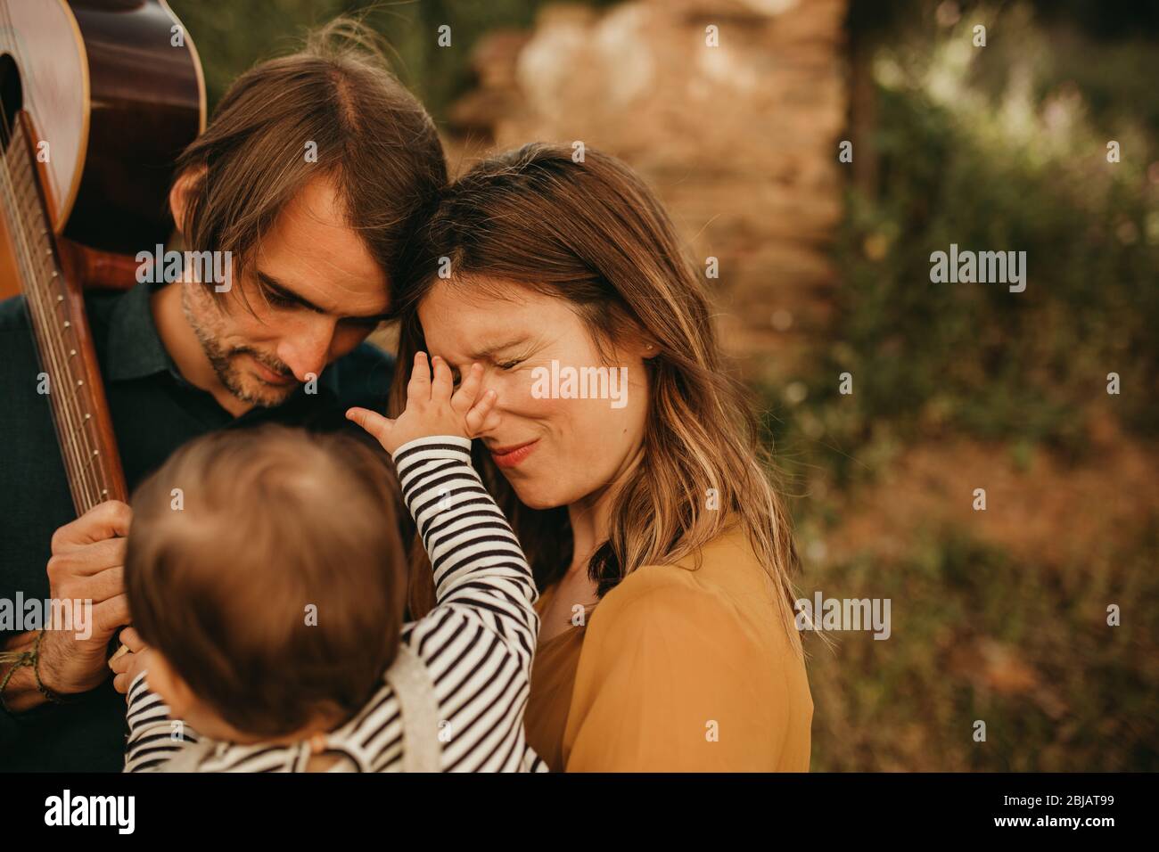 Lustige Nahaufnahme Familienporträt von jungen Paar mit ihrem Baby Sohn. Säugling berührt sein Gesicht und sie reagiert mit geschlossenen Augen. Stockfoto