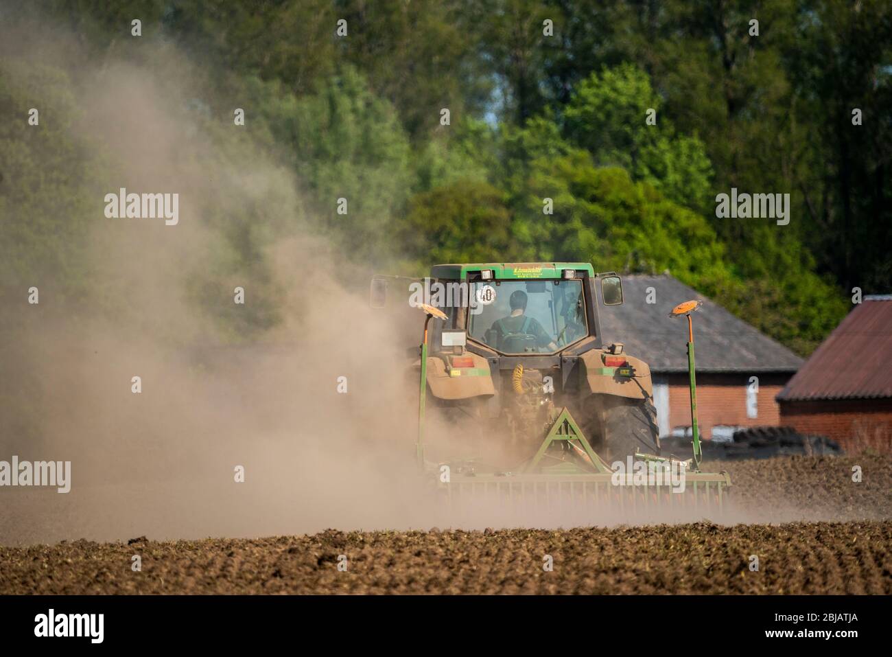 Bauer, der die Felder im Frühjahr, trocken April 2020, Traktor zieht dicke Staubwolke, während der Kultivierung, lockern den Boden, hinter ihm, Niederrhein Stockfoto