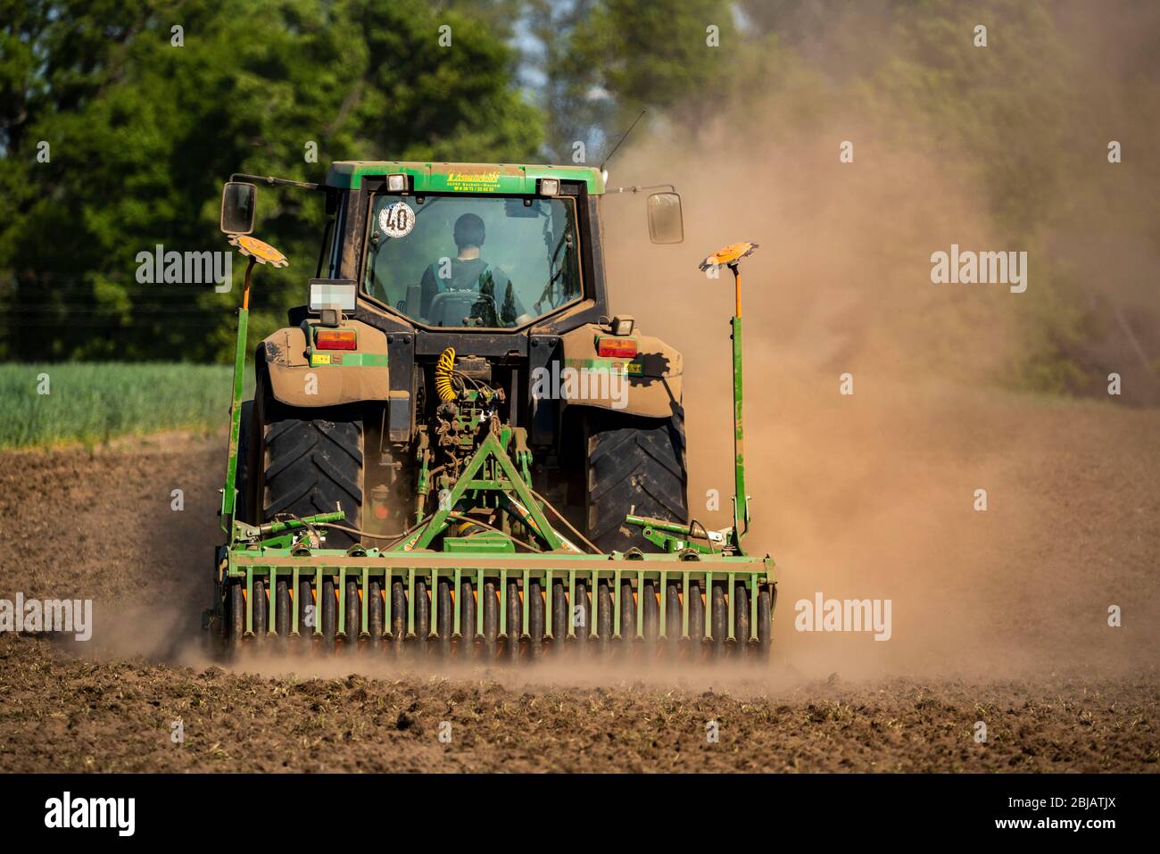 Bauer, der die Felder im Frühjahr, trocken April 2020, Traktor zieht dicke Staubwolke, während der Kultivierung, lockern den Boden, hinter ihm, Niederrhein Stockfoto