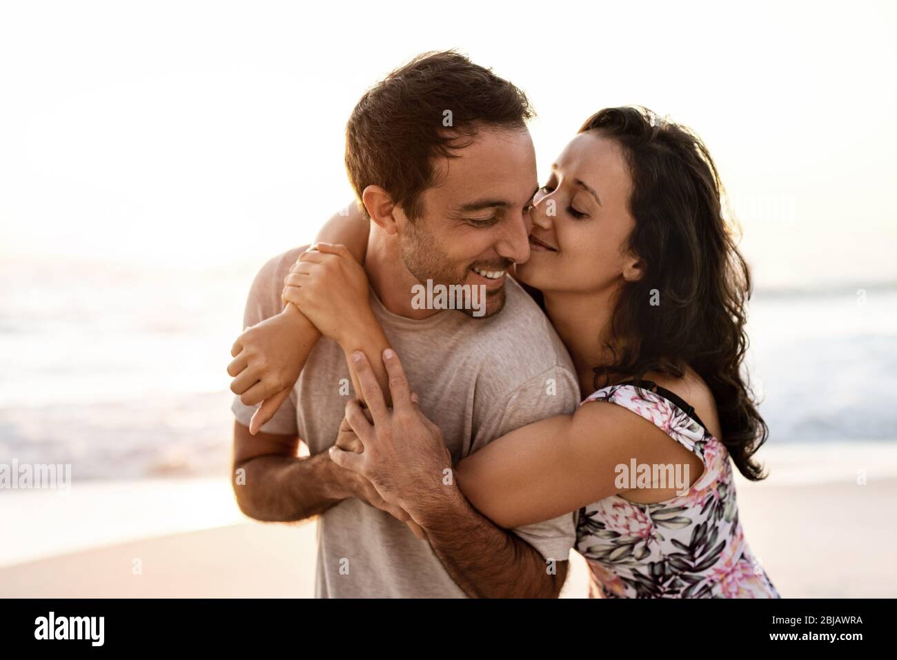 Liebende Paare, die Spaß am Strand bei Sonnenuntergang haben Stockfoto