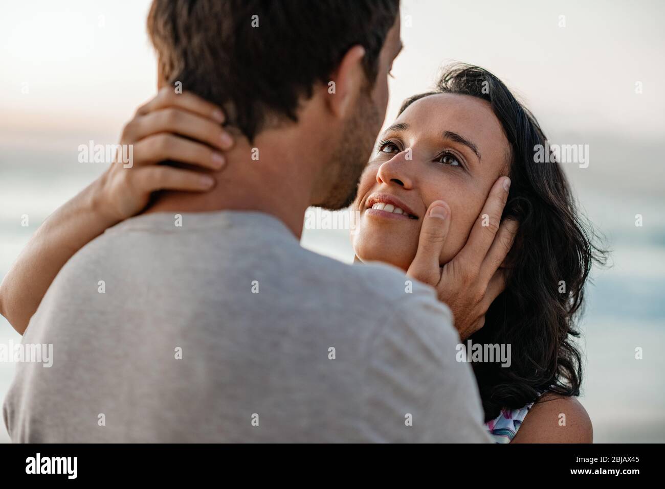 Junge Frau starrt ihrem Mann in die Augen am Strand Stockfoto