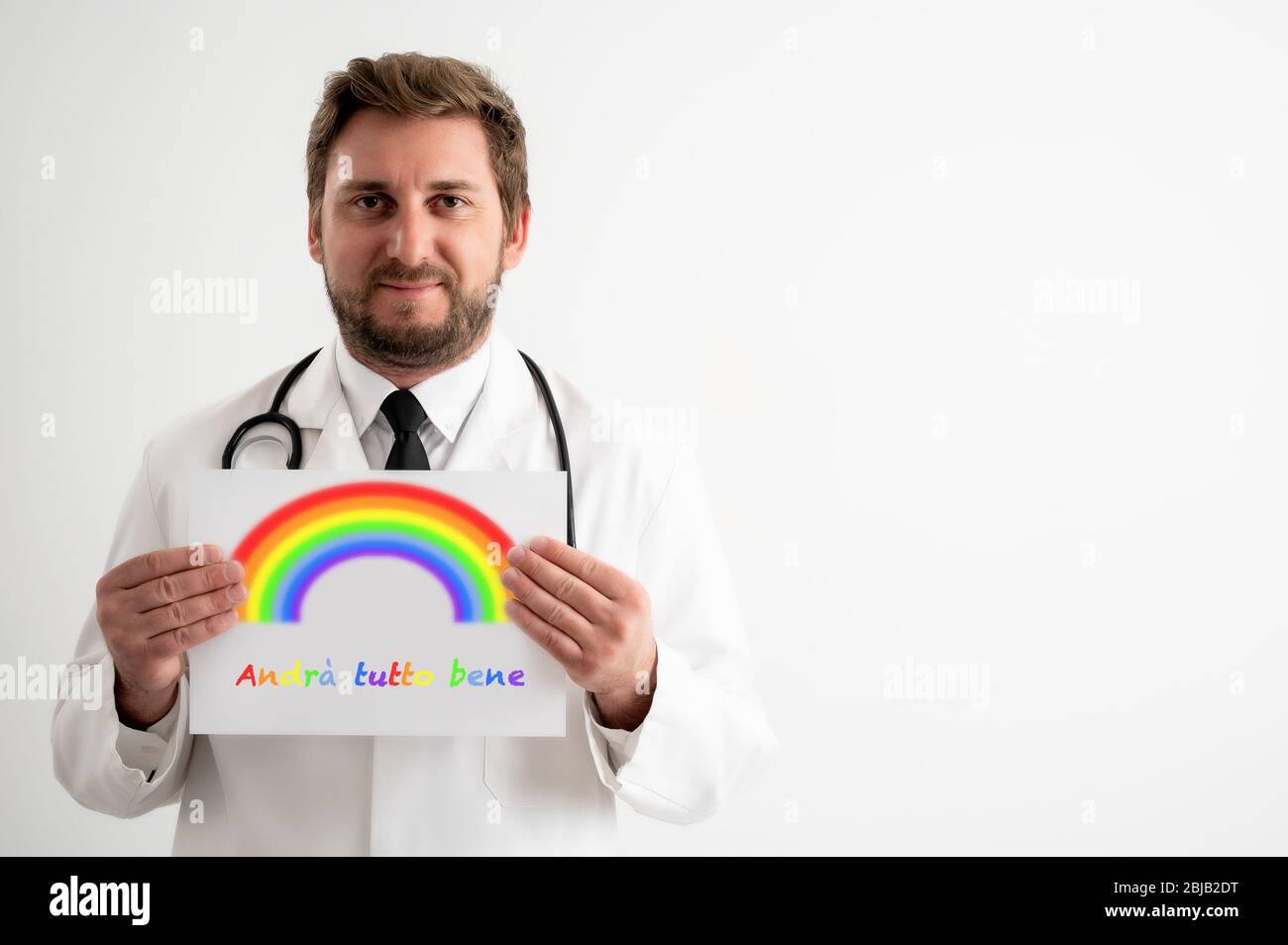 Porträt des männlichen Arztes mit Stethoskop in medizinischer Uniform, das ein weißes Papier mit Regenbogenbotschaft hält und lächelnd auf einem weißen isolierten Rückgro posiert Stockfoto