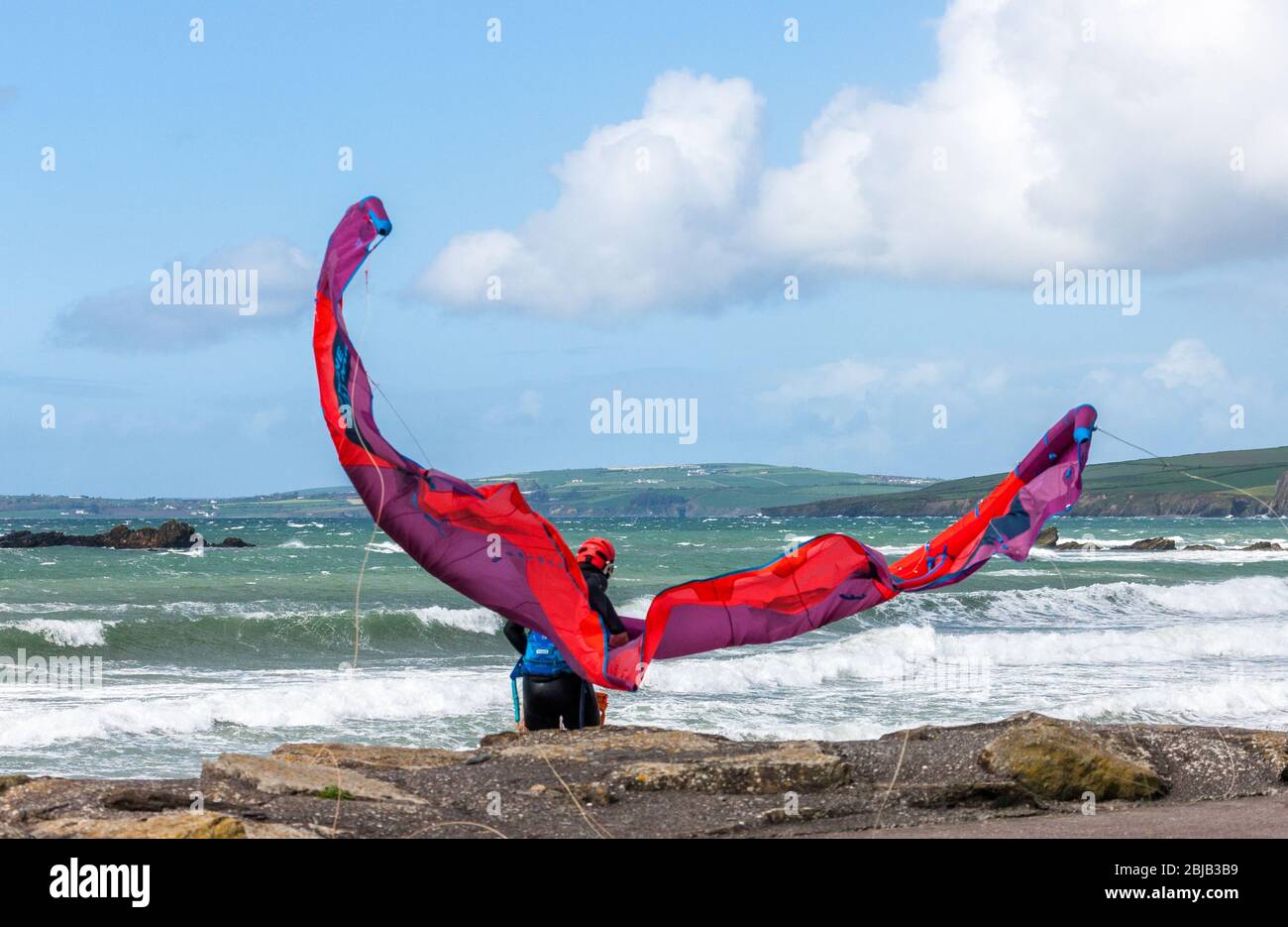 Garrettstown, Cork, Irland. April 2020. Ein Einheimischer kämpft, um seinen Drachen bei hohem Wind zu kontrollieren, während er sich auf einen Morgen des Surfens am Garrettstown Beach in Co. Cork, Irland, vorbereitet. - Credit; David Creedon / Alamy Live News Stockfoto