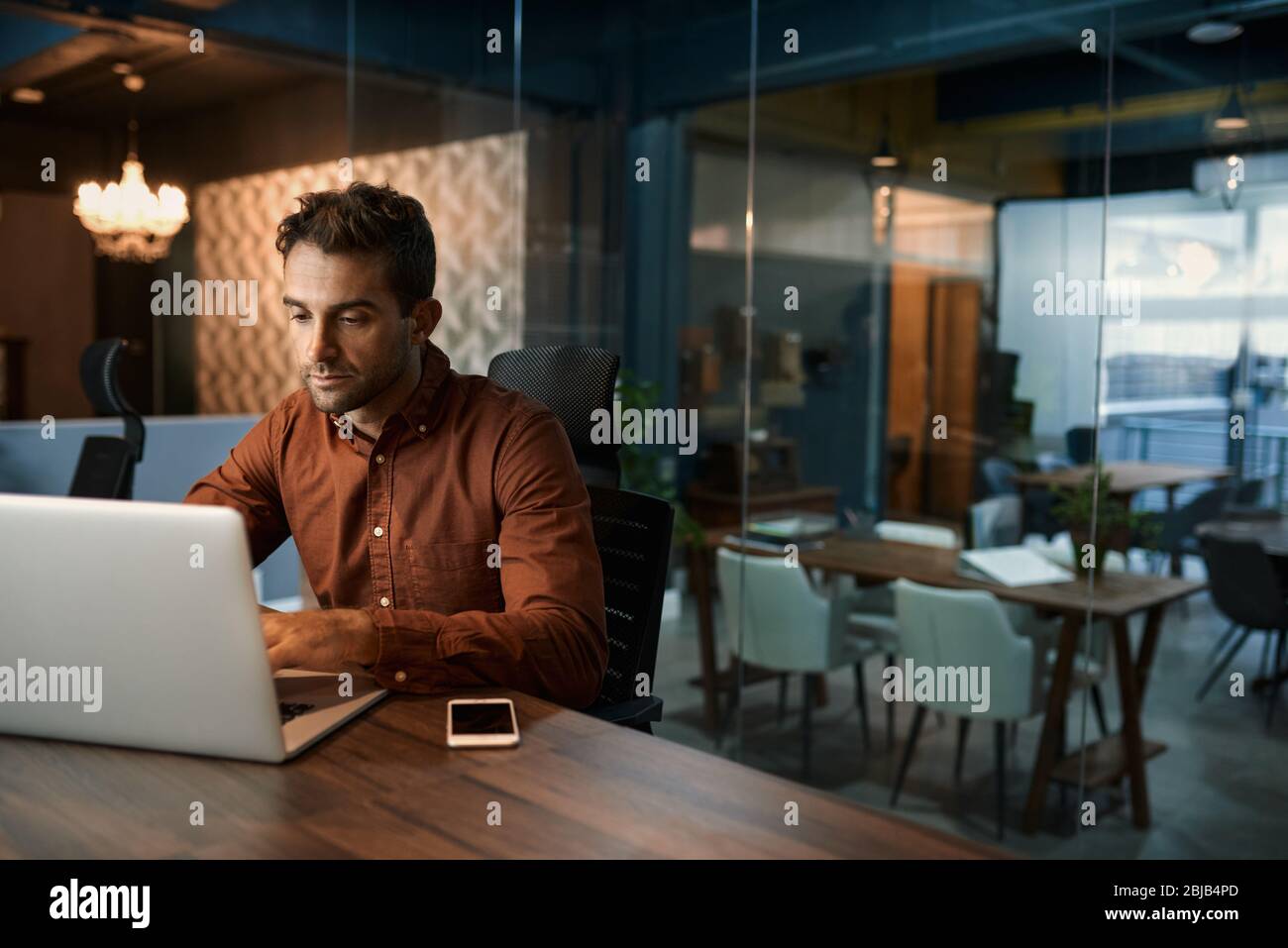 Geschäftsmann, der nach Stunden im Büro an seinem Laptop arbeitet Stockfoto