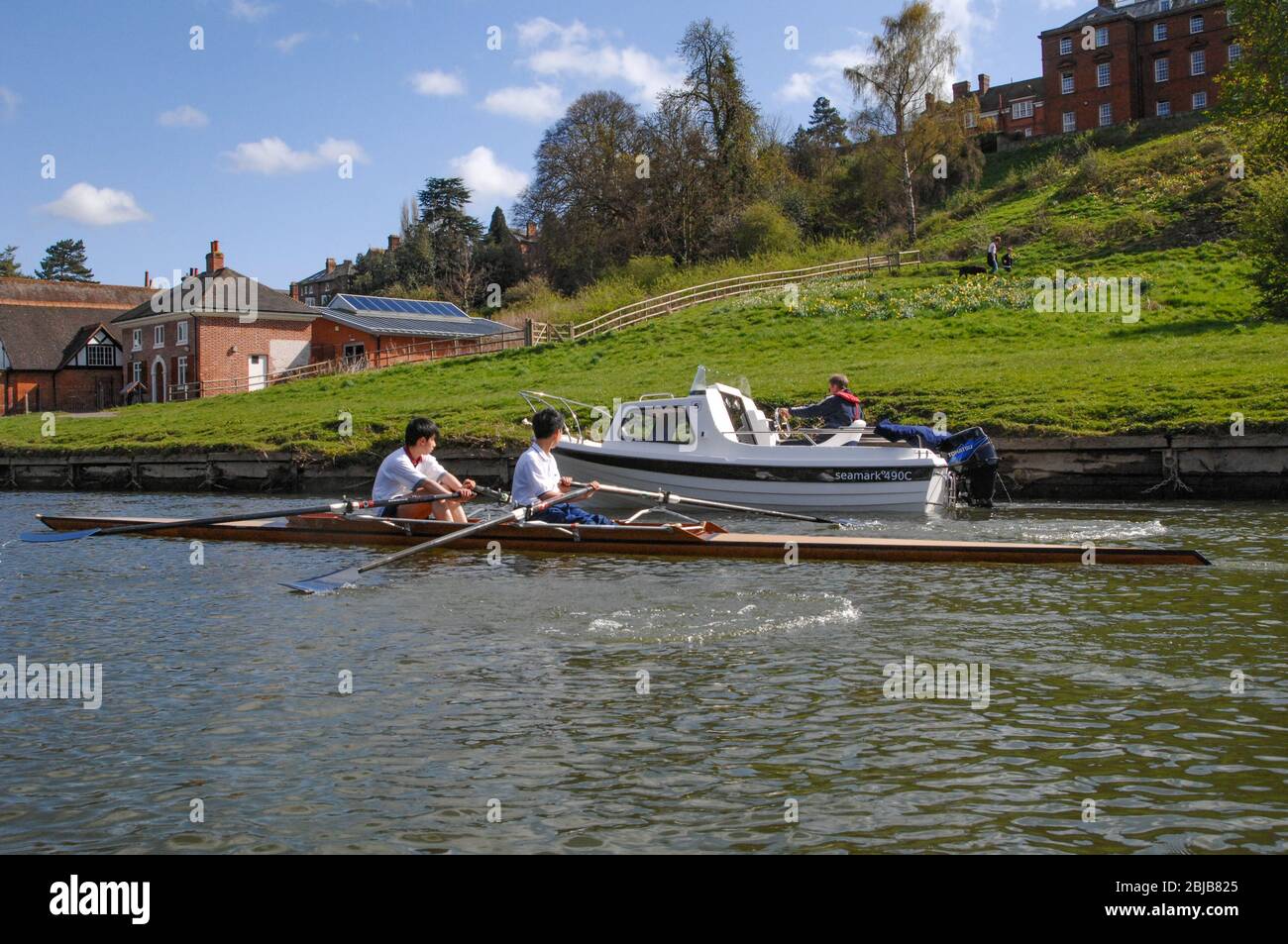 Zwei Männer in einer Rudern Scull Blick auf ein motorbetriebenes Boot sie auf dem Fluss Severn in Shrewsbury UK passieren Stockfoto