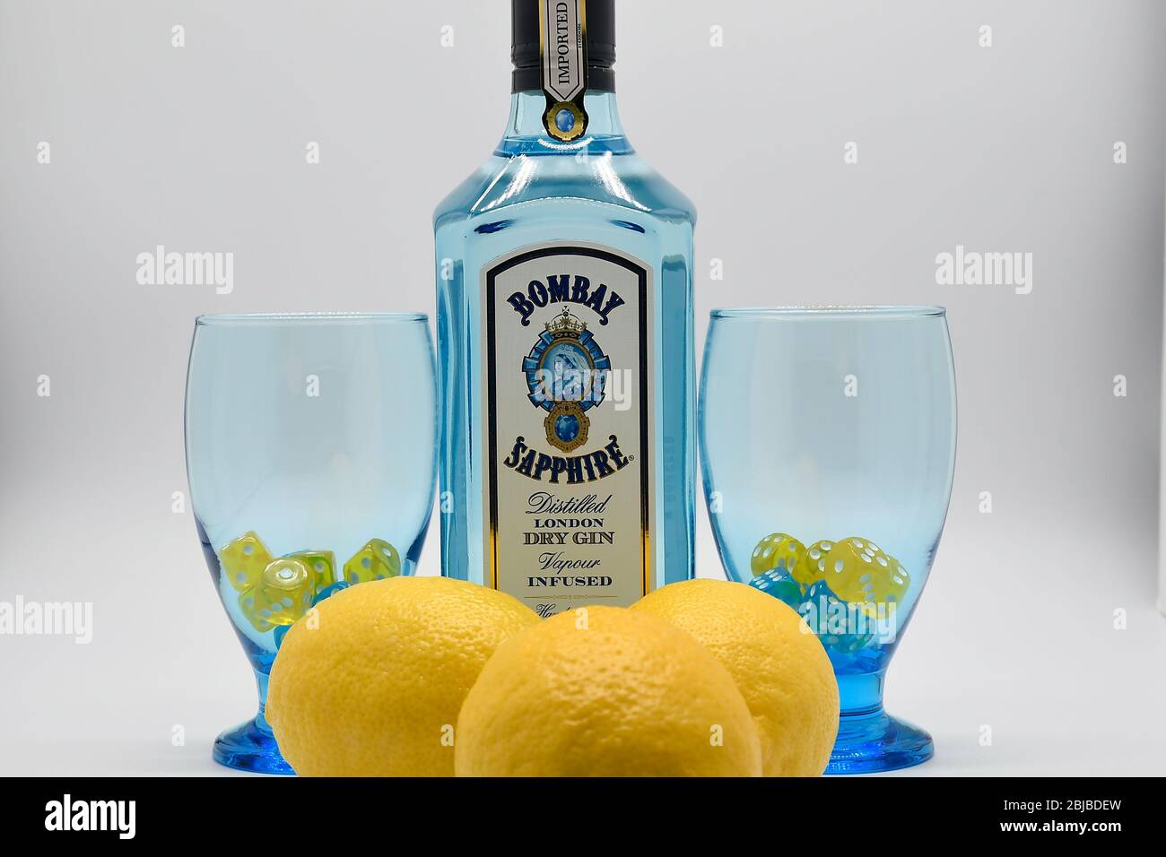 Flasche Bombay Sapphire Gin mit zwei Kelchen und Zitronen weißen Hintergrund Stockfoto