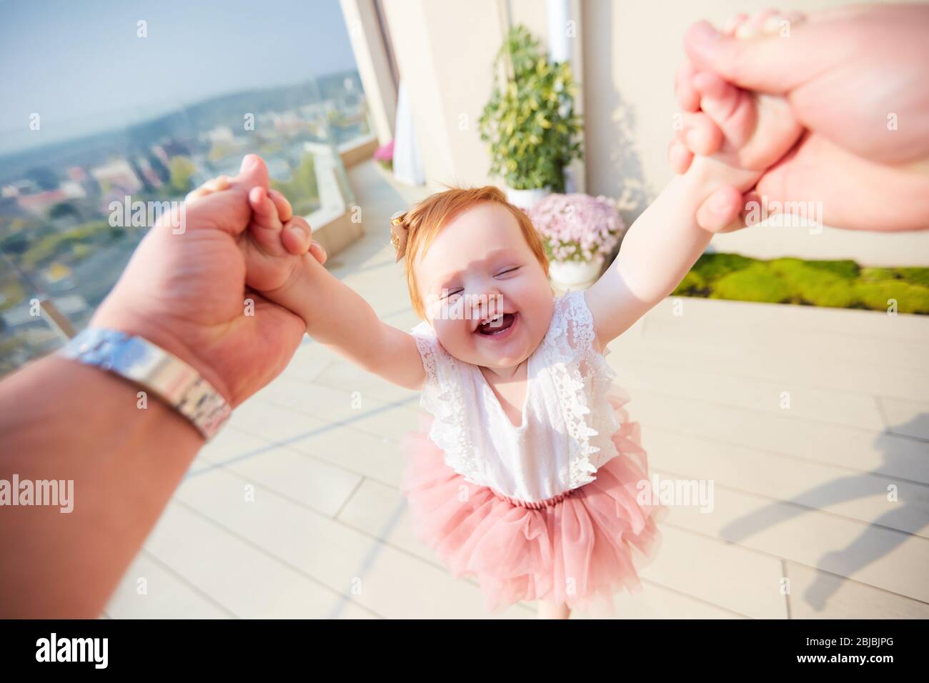 Glückliches Baby Baby Mädchen dreht sich in einem Kreis von Vater, Familienzeit Stockfoto