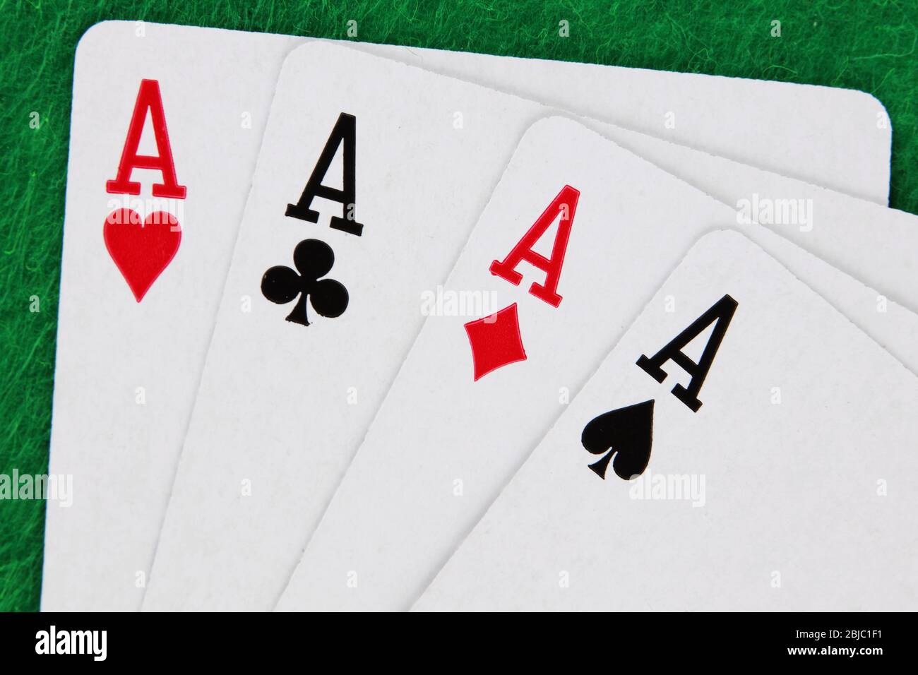 Eine Runde von vier Assen mit grünen Casino-Tisch im Hintergrund gewinnende Hand Stockfoto