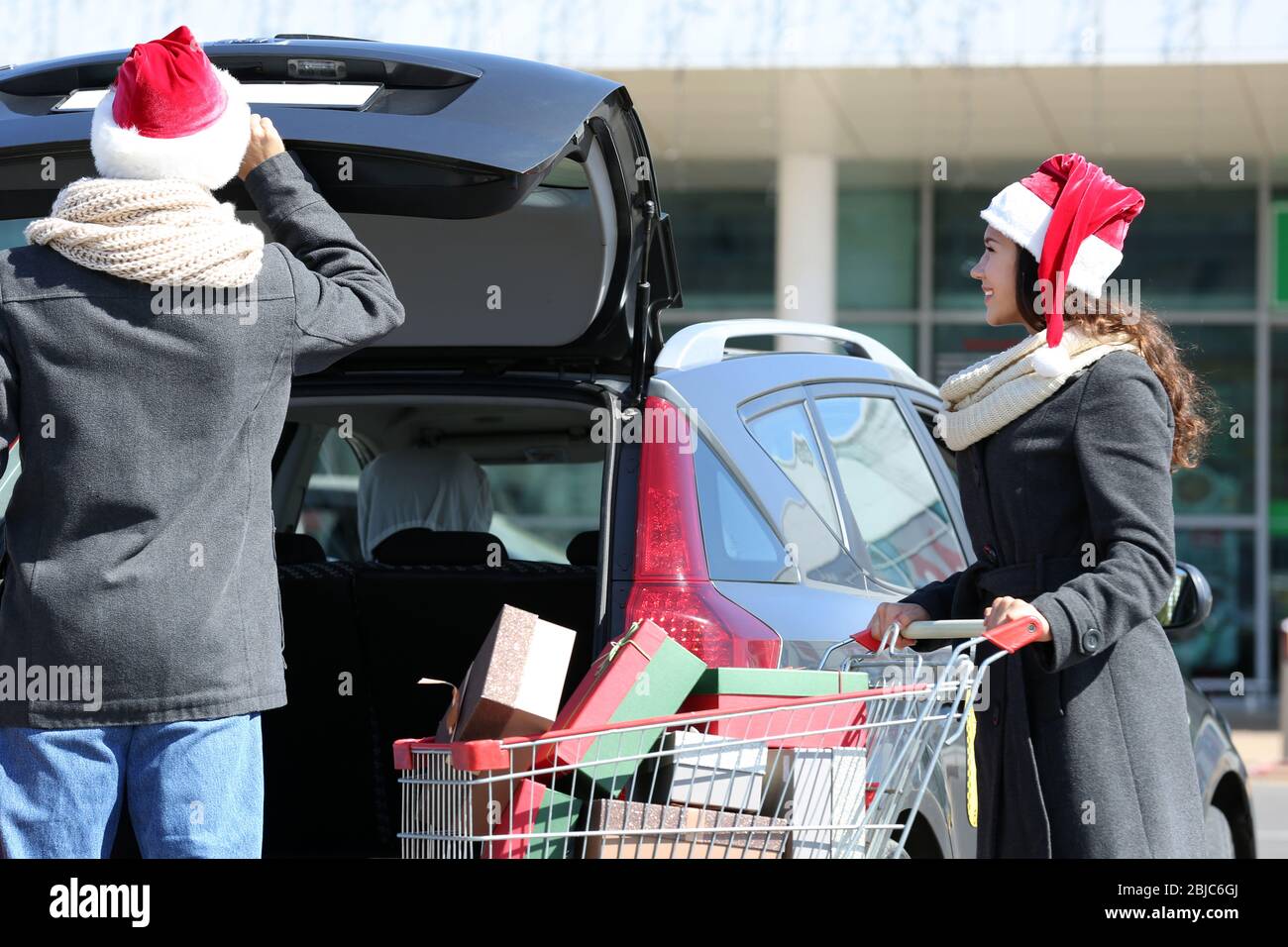 Junges Paar lädt Weihnachtseinkäufe in Autokoffer auf dem Parkplatz des Einkaufszentrums Stockfoto