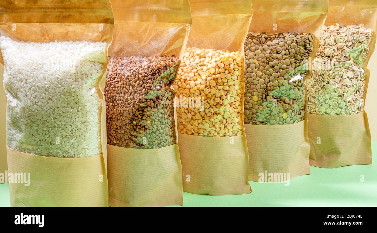 Papiertüten mit Zellophan voller Getreide und Hülsenfrüchte Nahaufnahme. Buchweizen, Erbsen, Linsen, Reis, Haferflocken. Konzept Der Lagerung Von Lebensmitteln Ohne Abfall. Kein Plast Stockfoto