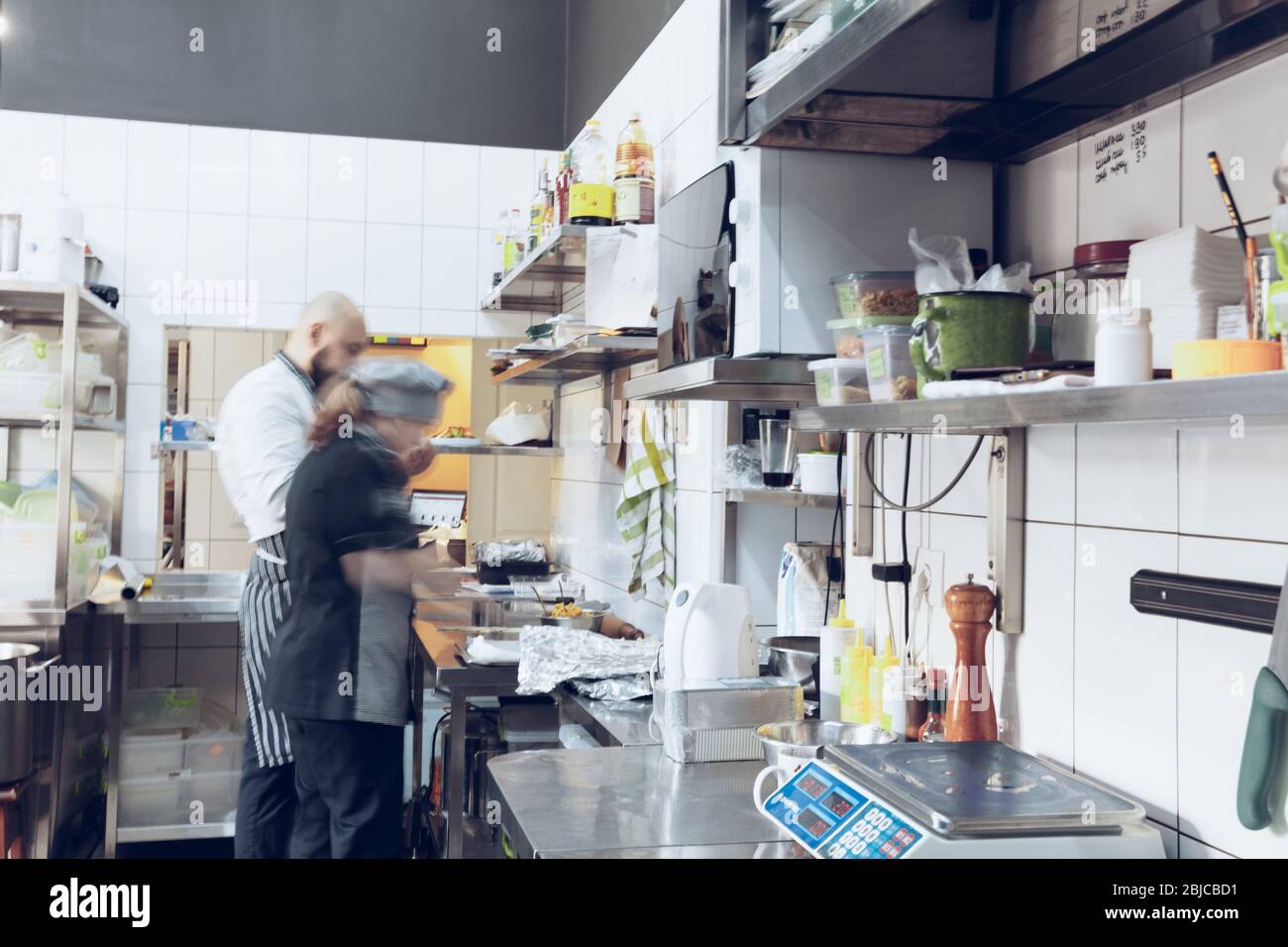 Hinter den Kulissen von Marken. Der Koch kocht in einer professionellen Küche eines Restaurants Mahlzeit für Kunden oder Lieferung. Öffnen Sie Ihr Geschäft von innen. Mahlzeiten während der Quarantäne. Schnell nach oben, Bewegung. Stockfoto